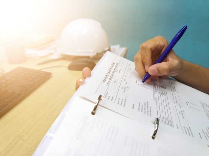 Engineer inspecting and checking datasheet.Engineers check the preventive maintenance documents after the operation.