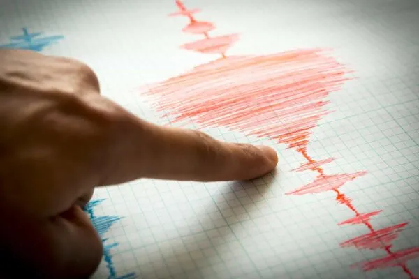 Seismological device for measuring earthquakes. Seismological activity lines on the sheet of measuring paper. Earthquake wave on graph paper. Vignette image. Human finger showing a detail. | Devin Hougard Joins CTL|Thompson as Staff Engineer