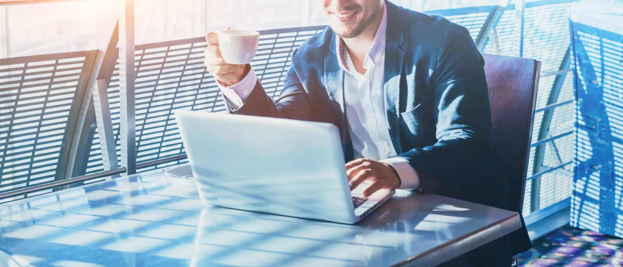 businessman working on computer, drinking coffee and smiling, abstract  business banner background with place for text - Civil + Structural  Engineer magazine