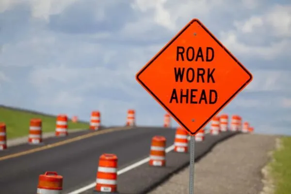 Road construction zone with orange warning sign. | 30 Universal Work Zone Safety Tips