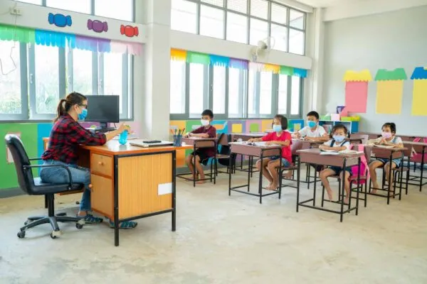 Group of school kids wearing protective mask to Protect Against Covid-19 with teacher sitting in classroom,education,elementary school,Social Distancing,learning and people concept. | Preparing Schools for a Safe Reopening: Recommendations for HVAC Maintenance and Support