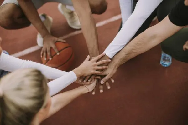 Overhead view of basketball team holding hands over court | From the Publisher – February