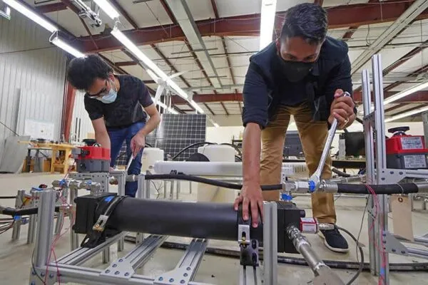 Graduate students Abhimanyu Das (left) and Akshay Rao adjust a piston tank, the key component to a new desalination process called “double-acting batch reverse osmosis.” (Purdue University photo/Jared Pike) | Breakthrough in reverse osmosis may lead to most energy-efficient seawater desalination ever