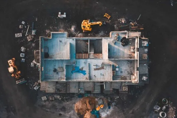 Aerial birds eye image of the frame of a house being built on a construction site at sunset - Wooden floor and walls are visible | Total Construction Starts Decline in August