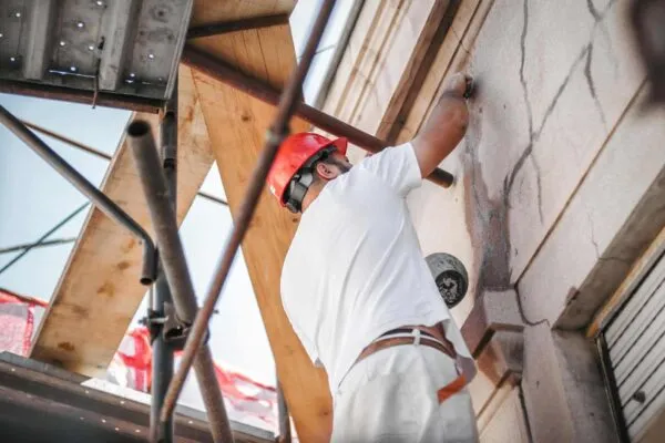 Man worker standing on scaffolding, perform work on the restoration of the facade of the old building. Repairing and renovate | Loring Expands Mid Atlantic Presence
