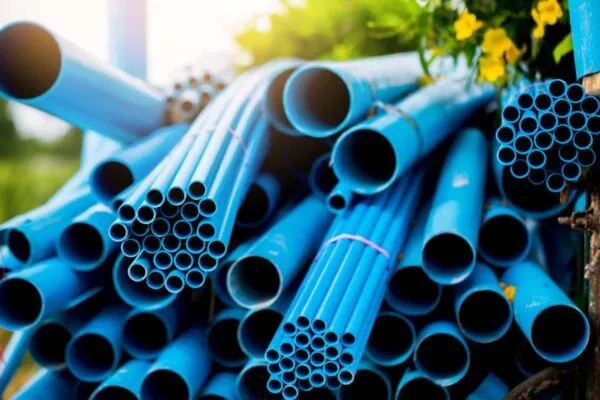 Selective to blue plastic pipe background. PVC pipes stacked in warehouse of construction site.  PVC water pipes used for construction. | Lifting a Community, a Holistic Approach
