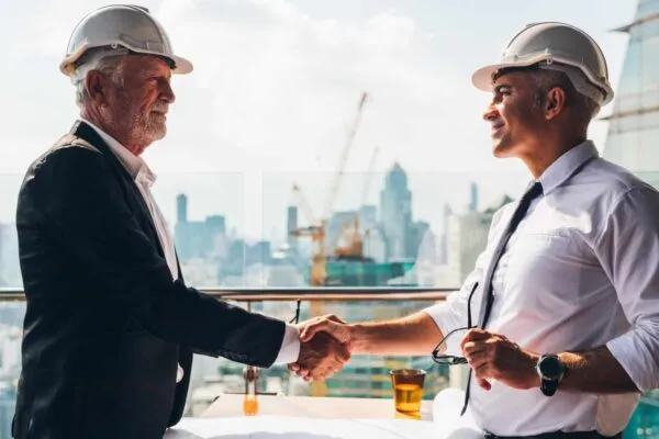 Two engineer wear safety helmet shaking hands after meeting for architectural project working with partner. Worker and customer having agreement in factory. Industry, Engineering, construction concept. | Bowman Expands Building Services and M/E/P Practices Through Acquisition of PCD Engineering, Inc.