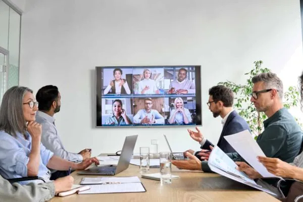 Diverse company employees having online business conference video call on tv screen monitor in board meeting room. Videoconference presentation, global virtual group corporate training concept. | Exponent to Announce Third Quarter of Fiscal Year 2021 Results and Host Quarterly Conference Call on October 28