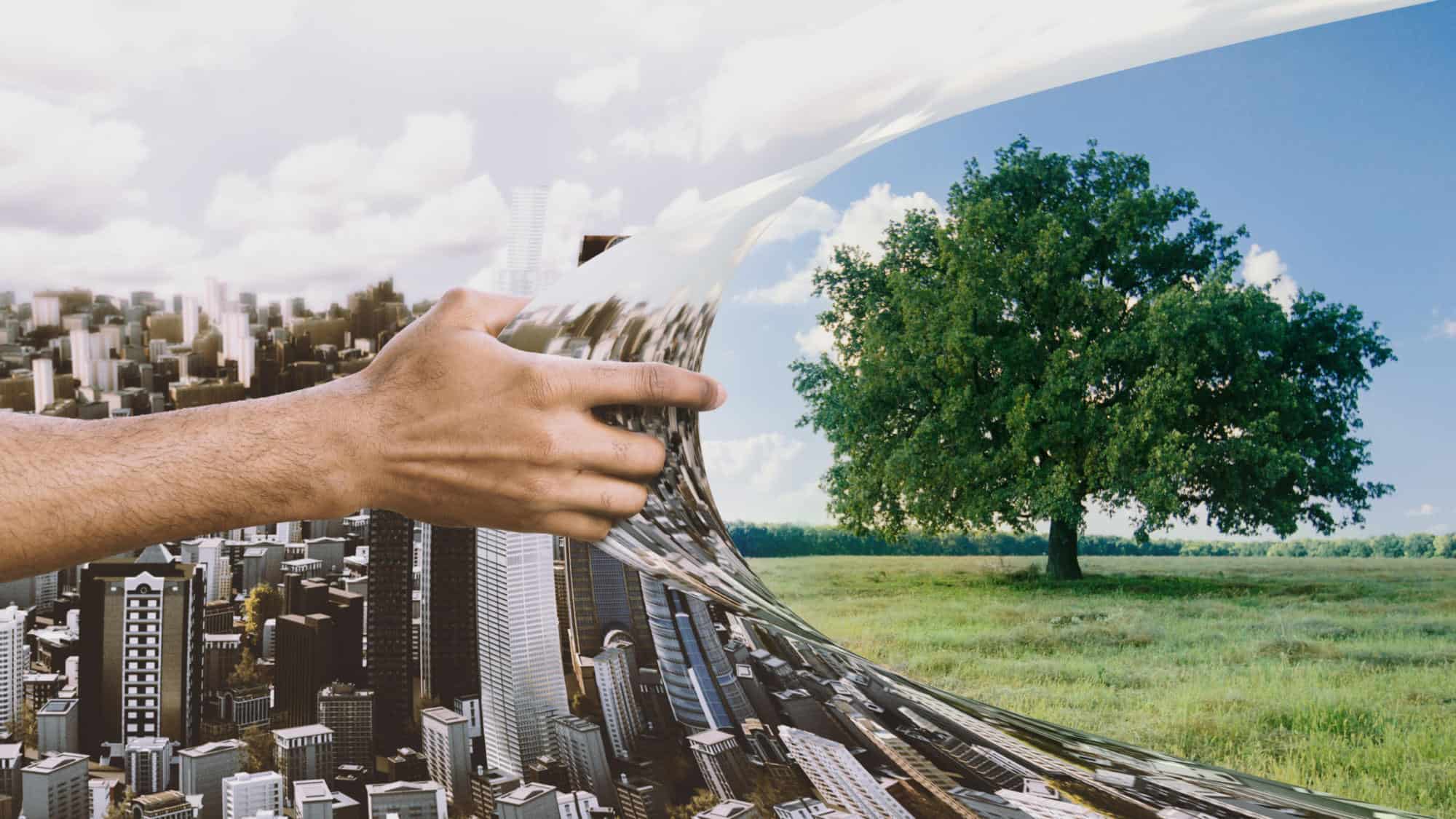 Urbanization and environment pollution. Male hand ripping off urban city picture out of green tree photo, panorama | COP26: Industry calls for action from government and business to address embodied emissions in building construction