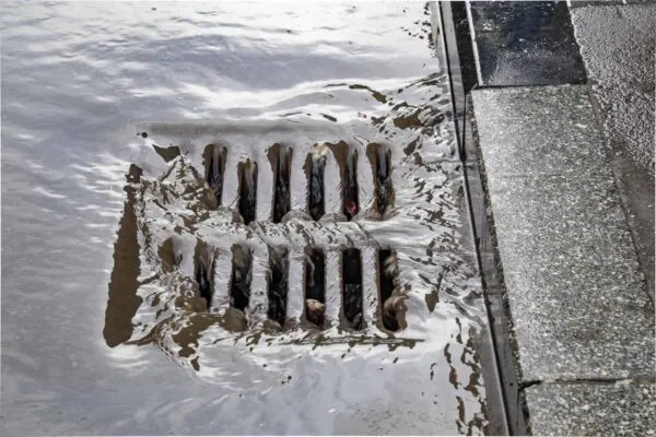 Rain flowing into a storm water sewer system. Stormwater street drain during heavy rain. | Advanced Drainage Systems Announces Acquisition of Jet Polymer Recycling