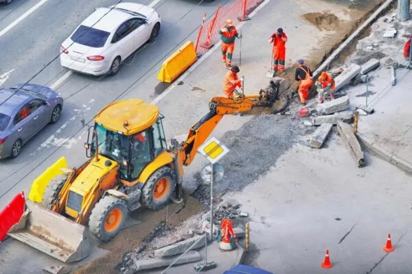 Bulldozer with group of workers wear safety uniform during road works in an asphalt road. New kerb stones on gravel ground placing road edge at construction site. Machine labor builder digging highway | TranSystems Acquires Chicago-Based OMEGA