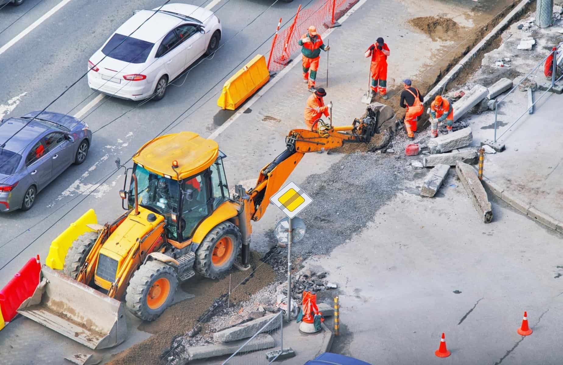 Bulldozer with group of workers wear safety uniform during road works in an asphalt road. New kerb stones on gravel ground placing road edge at construction site. Machine labor builder digging highway | TranSystems Acquires Chicago-Based OMEGA