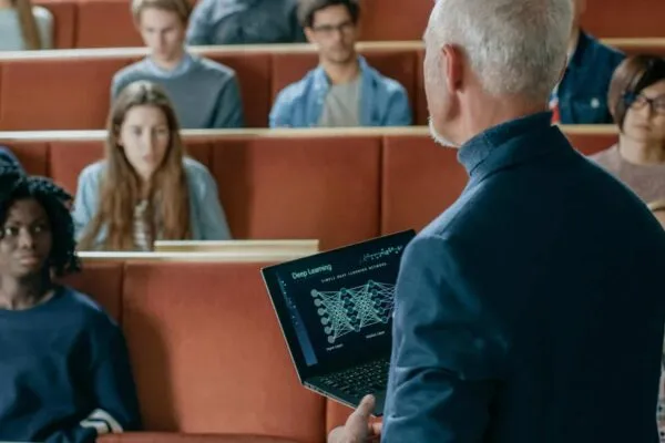 Professor of Computer Science Reads Lecture to a Classroom Full of Multi Ethnic Students. Teacher Holds Laptop with Deep Learning, Artificial Intelligence Infographics on the Screen. | Terracon Foundation Awards $183,094 in Grants