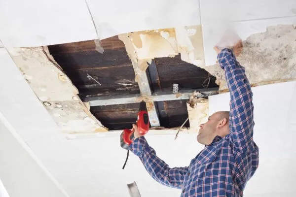 Man repairing collapsed ceiling. Ceiling panels damaged  huge hole in roof from rainwater leakage.Water damaged ceiling . | Bryter Restoration of Wilmington Announce A 24/7 Service Model for Water Damage Restoration and Repair In North Carolina