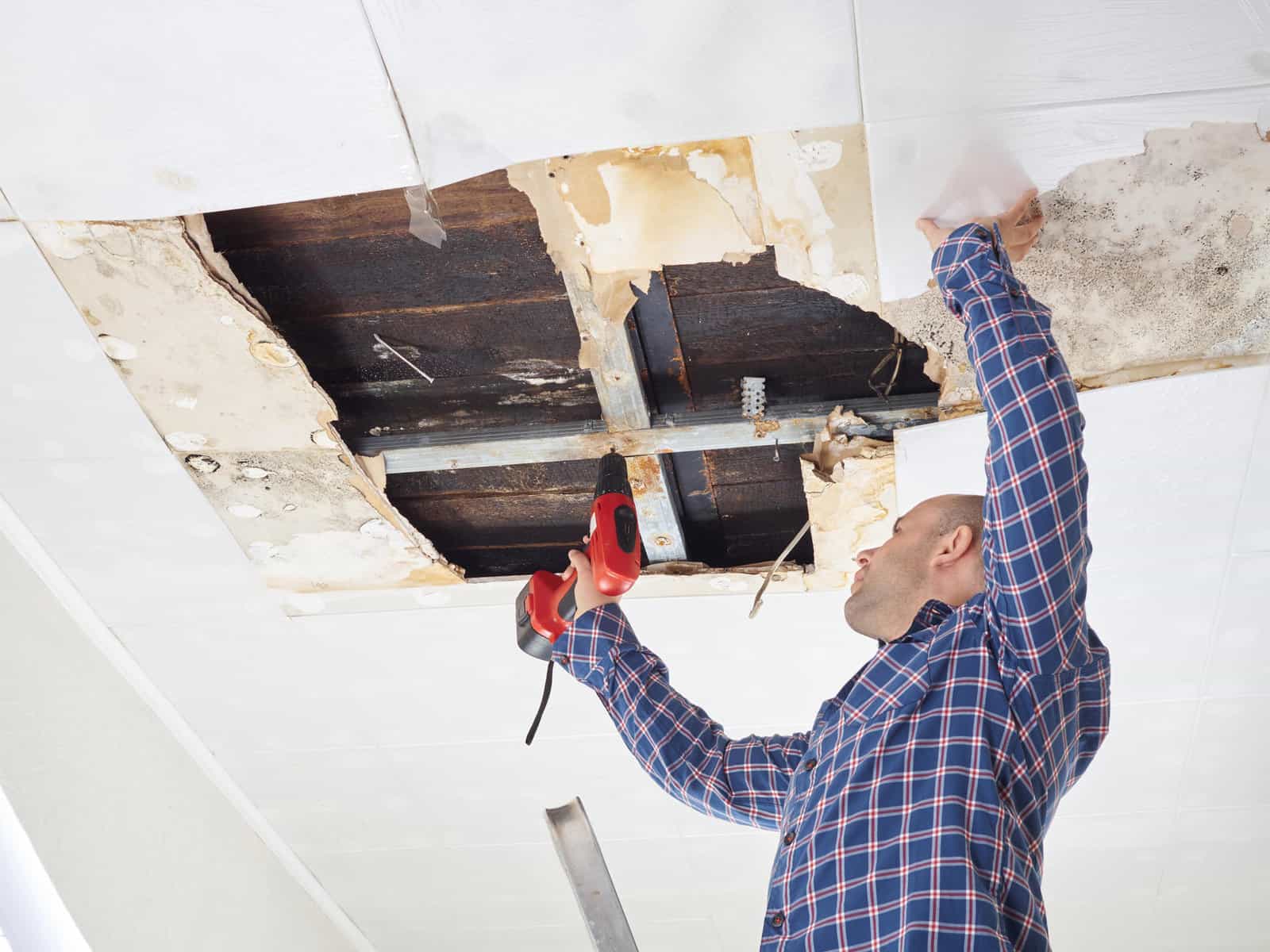 Man repairing collapsed ceiling. Ceiling panels damaged  huge hole in roof from rainwater leakage.Water damaged ceiling . | Bryter Restoration of Wilmington Announce A 24/7 Service Model for Water Damage Restoration and Repair In North Carolina