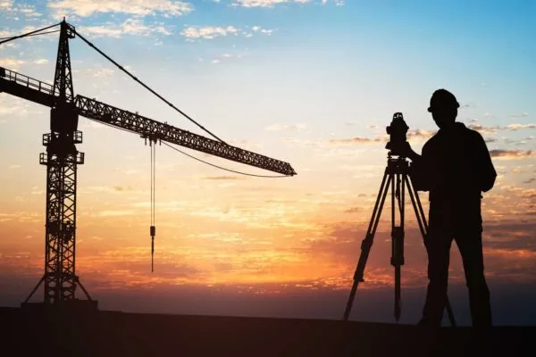 Silhouette Of A Surveyor Standing With Equipment Near Crane At Construction Site During Sunset | EMPEQ Announces Relationship with RETScreen to Increase Speed and Accuracy of Energy Audits by 80% for Users