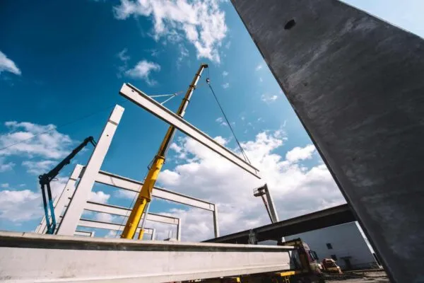 Construction site of prefabricated hall with cement pillars and concrete beams moving crane | CLARK PACIFIC PARTNERS WITH NEWGEN ENERGY, TRANSITIONS TO NEARLY 100% RENEWABLE ENERGY ACROSS ITS OPERATIONS
