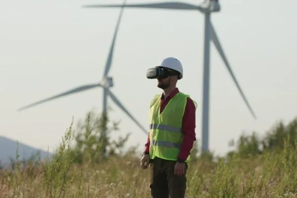 Engineer in VR glasses looking at graphs, turning pages. Windmills in the background. | MGISS partners with Leica Geosystems to drive a data-centric approach for Asset Managers