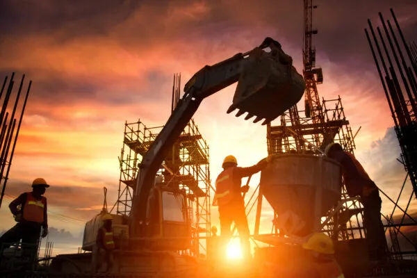 Silhouette Teams of Business Engineers looking for blueprints in construction sites through blurry construction sites at sunset. | Infrastructure costs keep rising. Consider these approaches to mitigate them.